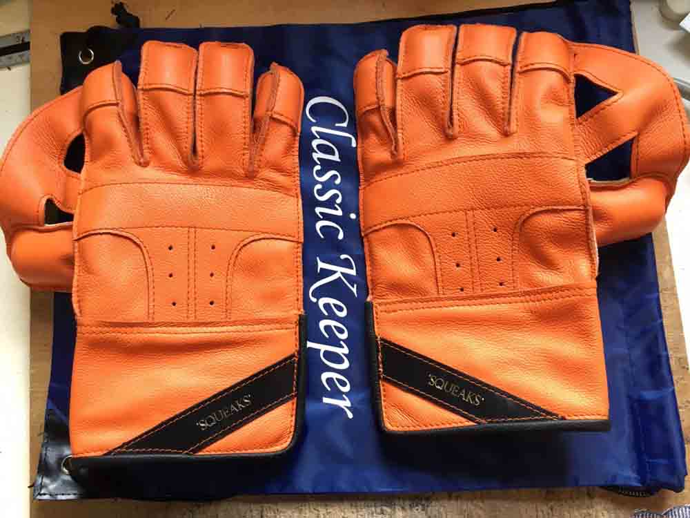 Orange wicket keeping gloves with black features